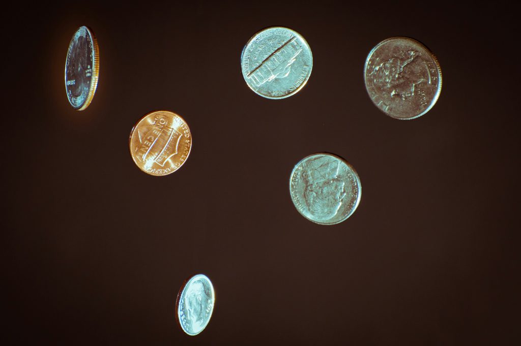 Coins suspended in mid-air against a dark background, visually representing the balance between luck and risk, chance and decision-making.